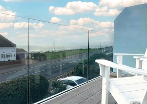 Detail view of glass railing balcony overlooking the Dorset coast.