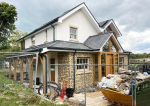 Front elevation of The Cottage with flint cladding and timber porch.