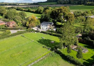 Distant aerial view of a contemporary cottage within a scenic rural English landscape.